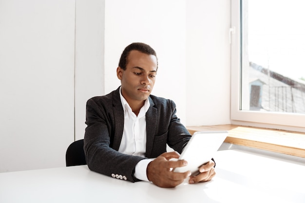 Young successful businessman looking at tablet, sitting  workplace