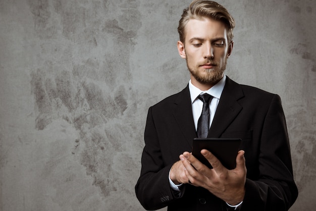 Free photo young successful businessman looking at tablet