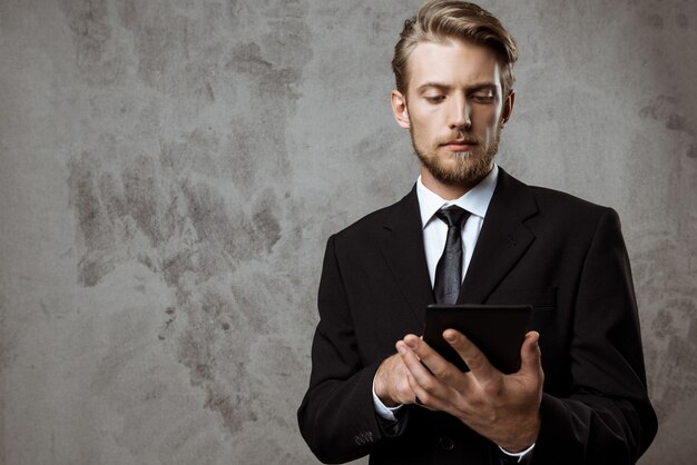 Young successful businessman looking at tablet