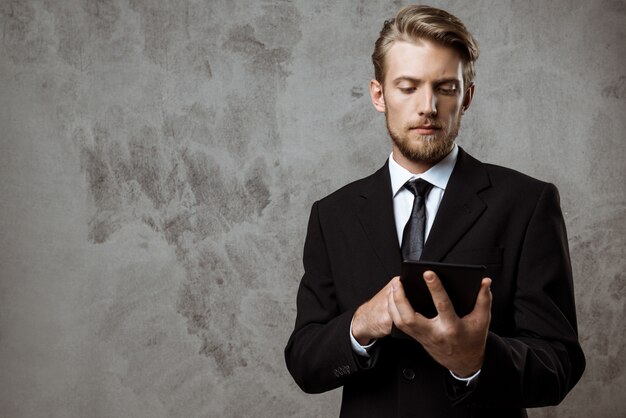 Young successful businessman looking at tablet