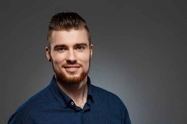 Young successful businessman posing over dark wall.