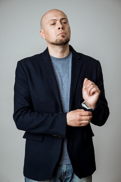 Free photo young successful businessman posing, fastening jacket over beige wall.