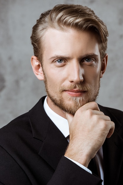 Young successful businessman posing with hand on chin