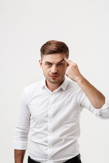 Young successful businessman raising eyebrow with finger.