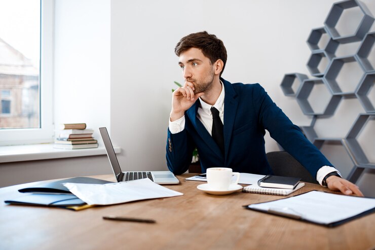 Free Photo young successful businessman sitting at workplace, office background.