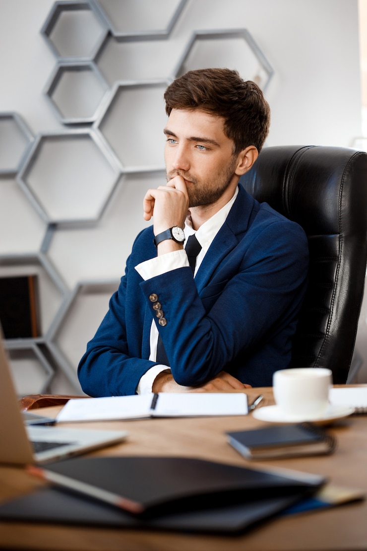 Free Photo young successful businessman sitting at workplace, office background.