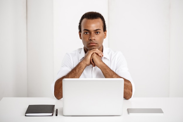 Young successful businessman sitting at workplace with laptop