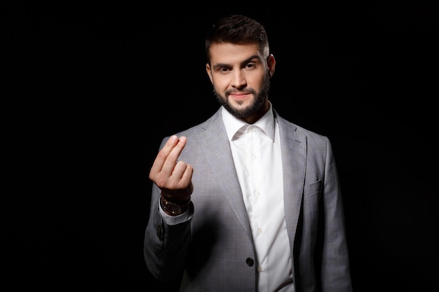 Young successful businessman in suit asking for money on black