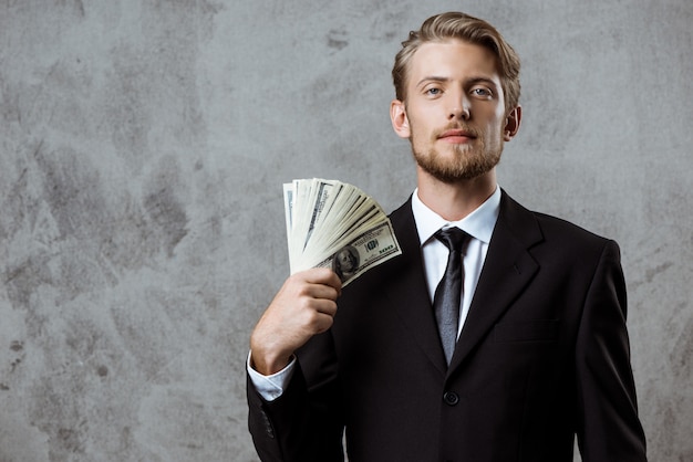 Young successful businessman in suit holding money