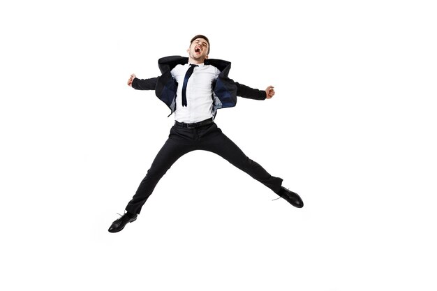 Young successful businessman in suit rejoising, jumping on white