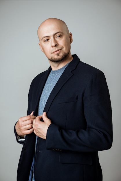 Young successful businessman thinking, posing over beige wall.