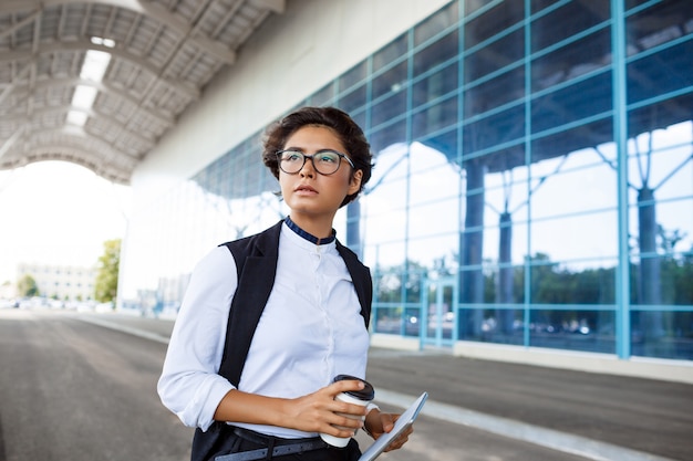 Free photo young successful businesswoman in glasses standing near business centre