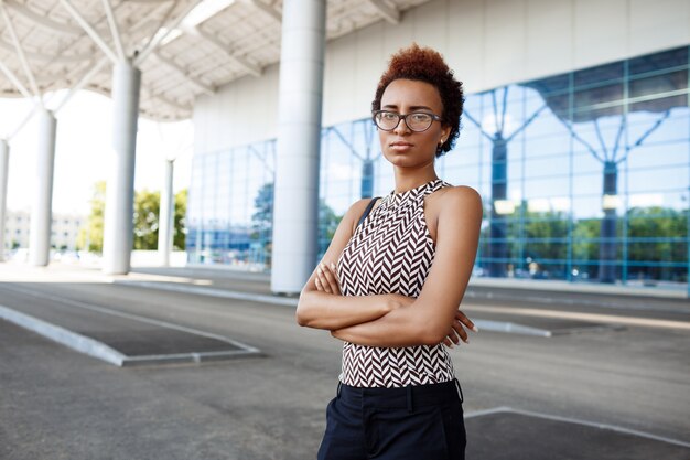 Young successful businesswoman in glasses standing near business centre