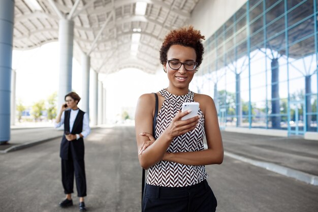 Young successful businesswoman looking at phone over business centre