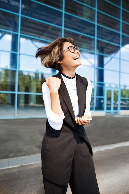 Foto gratuita giovane imprenditrice di successo sorridente, in piedi vicino al centro business.