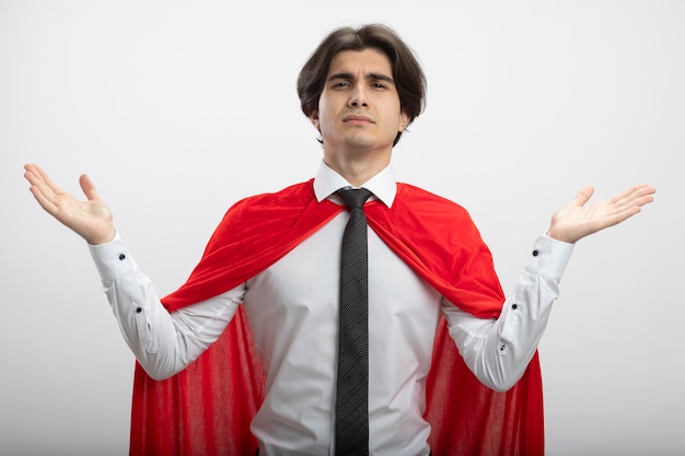 Young superhero guy looking at camera wearing tie spreading hands isolated on white background