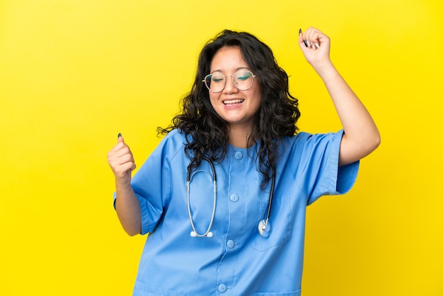 勝利​を​祝って​黄色​の​背景​に​分離された​若い​外科医​医師​アジア​の​女性