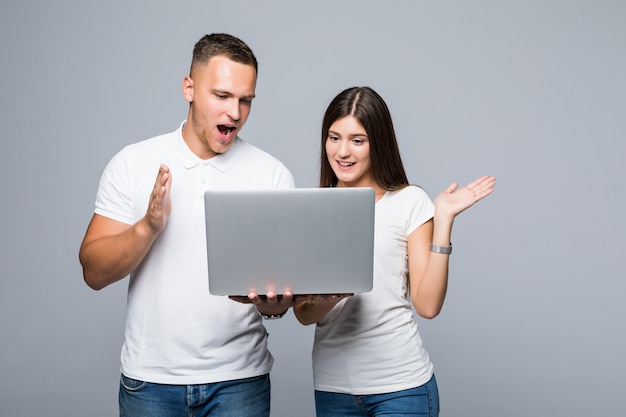 Young surprised couple in white tshirts watch something on brand laptop