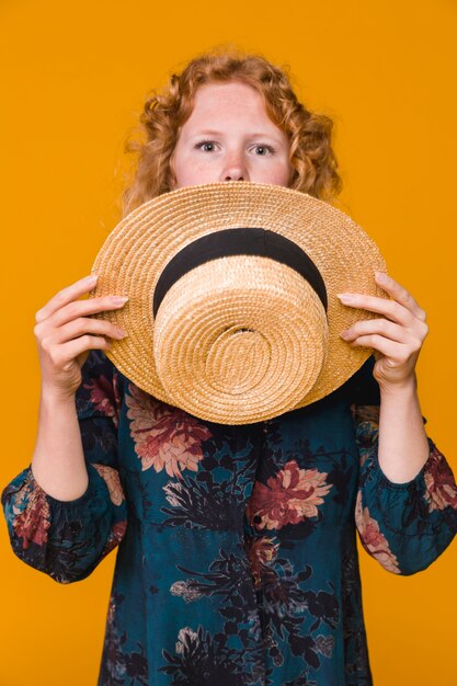 Young surprised female covering face with hat