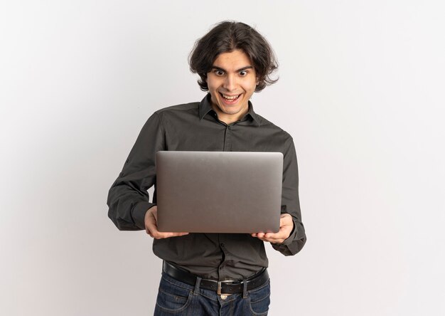 Young surprised handsome caucasian man holds and looks at laptop isolated on white background with copy space