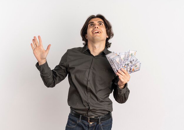 Young surprised handsome caucasian man holds money and looks up isolated on white background with copy space