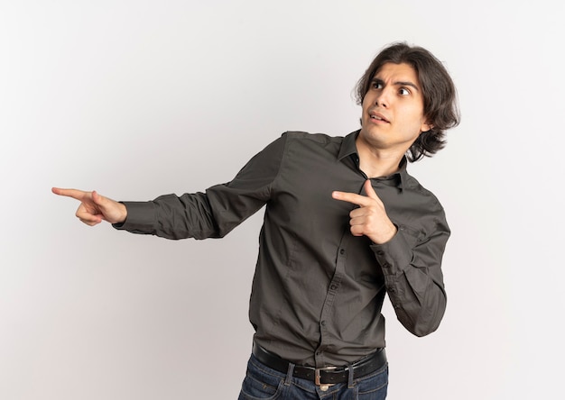 Young surprised handsome caucasian man looks and points at side isolated on white background with copy space