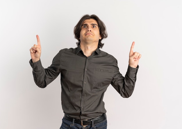 Young surprised handsome caucasian man looks and points up isolated on white background with copy space