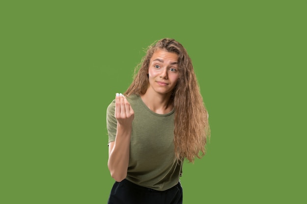 Young surprised woman against green wall