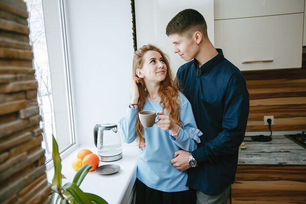 young and sweet lovely couple standing by the window in the kitchen