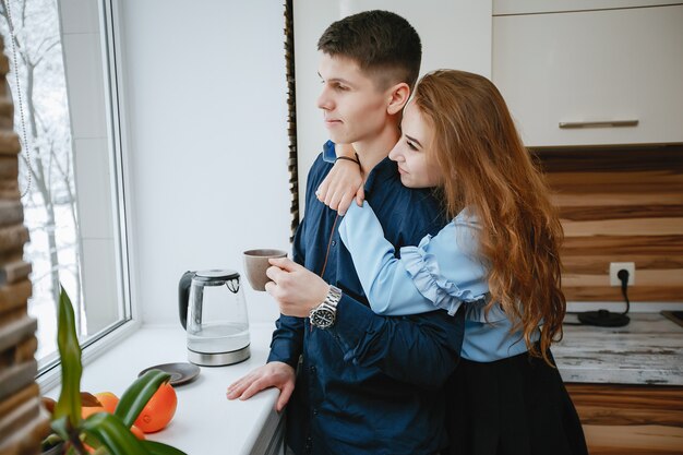 young and sweet lovely couple standing by the window in the kitchen