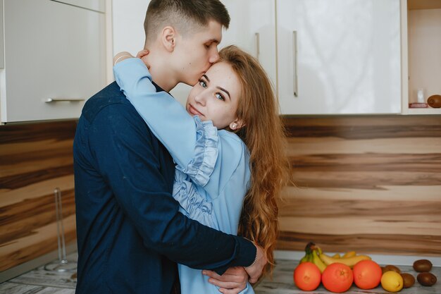 young and sweet lovely couple standing in the kitchen with fruits
