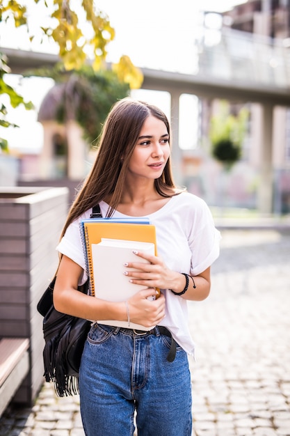 街を歩くカジュアルな服を着た若い才能のある女子学生。屋外の自由な時間を楽しんでいる魅力的なブルネットの女性