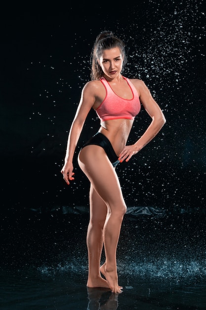 Young tanned fit woman with water drops