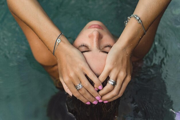 Free photo young tanned woman in the pool in frangipani flowers