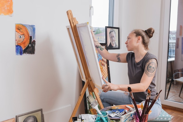 무료 사진 젊은 문신 여자 그림 그림 아트 스튜디오에 앉아