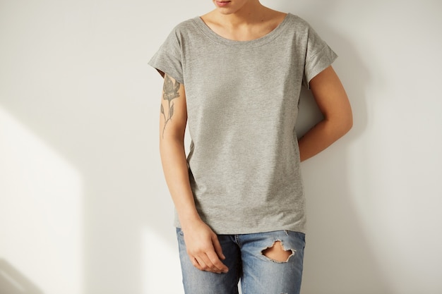 Молодая татуированная женщина в серой пустой футболке