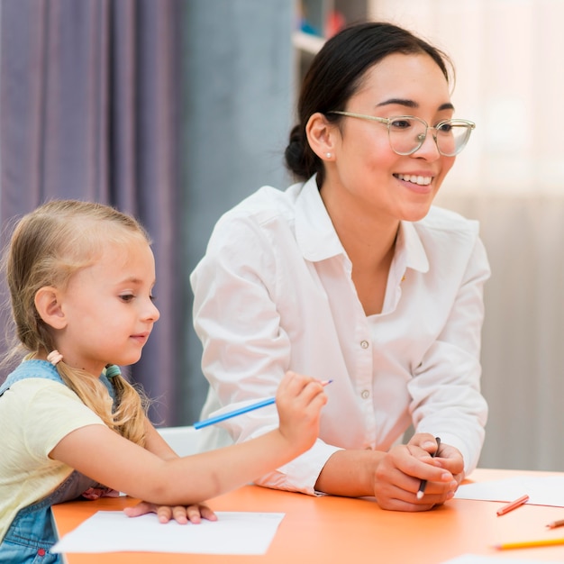 Young teacher helping little girl in class