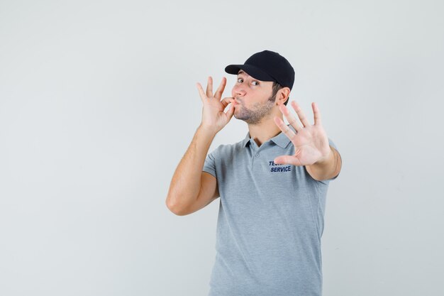 Young technician in grey uniform showing stop gesture with mouth shut as zip.