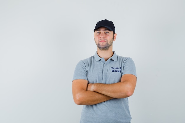 Young technician standing with crossed arms in uniform and looking confident.