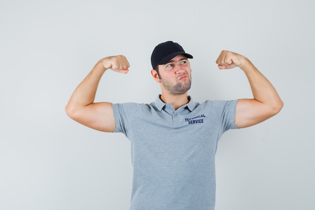 Free photo young technician in uniform showing muscles of arms and looking confident.