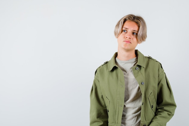 Young teen boy in green jacket looking upward and looking pensive