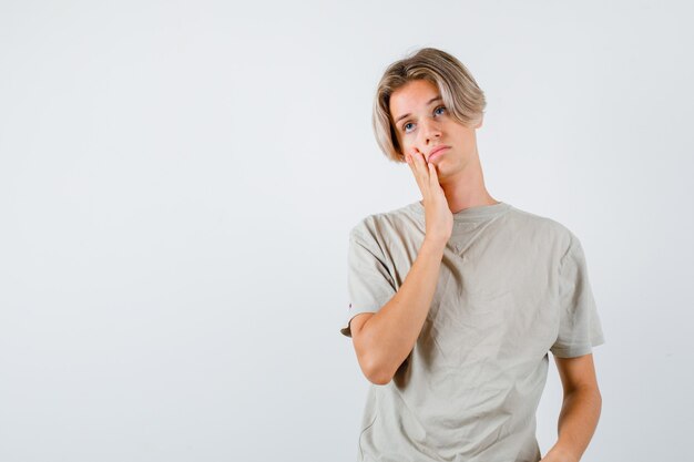 Young teen boy leaning cheek on hand