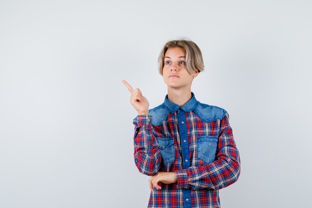 Young teen boy pointing at upper left corner