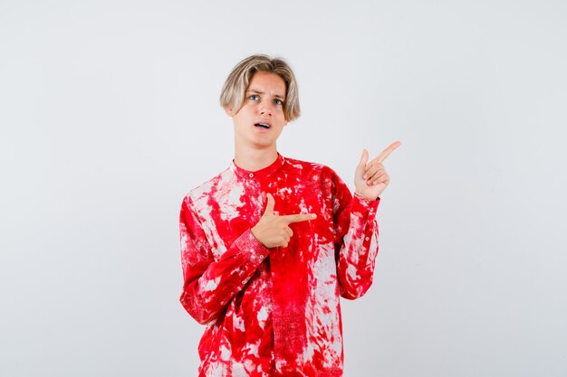 Young teen boy pointing at upper right corner, looking up in shirt and looking thoughtful. front view.