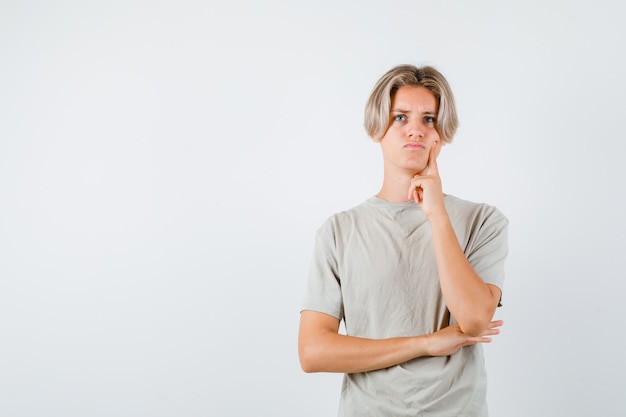 Young teen boy pressing finger on cheek