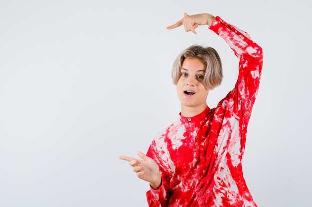 Young teen boy in shirt pointing left and looking glad , front view.