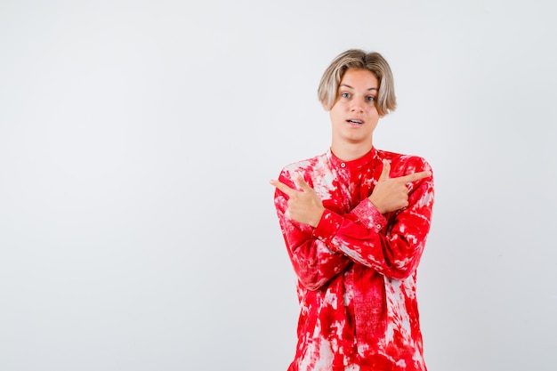 Young teen boy in shirt pointing to the opposite directions and looking indecisive , front view.