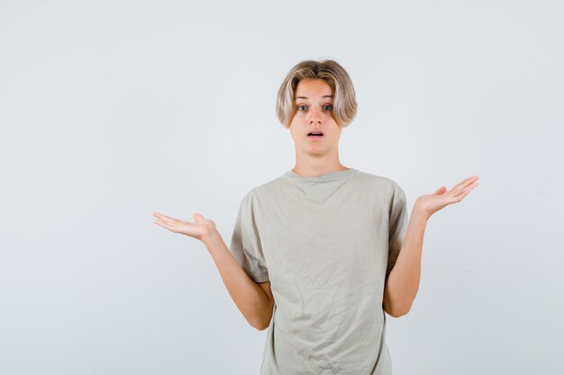 Young teen boy showing helpless gesture in t-shirt and looking puzzled. front view.