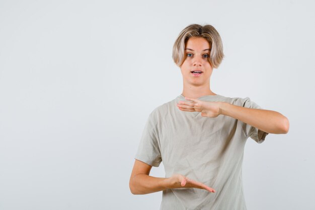 Young teen boy showing large size sign in t-shirt and looking wondered