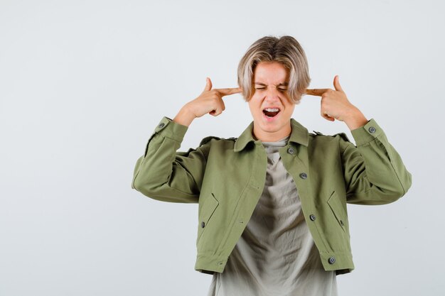 Young teen boy showing suicide gesture in t-shirt, jacket and looking resolute. front view.